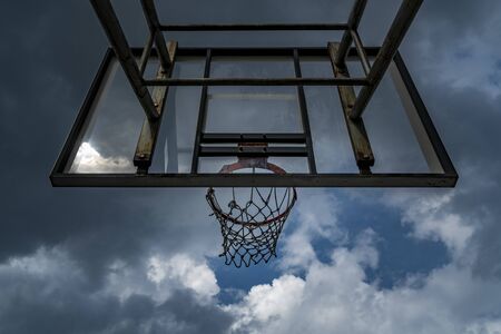 Basketball hoop with sky and black clouds before rain, perspective view, worm eye view.の写真素材