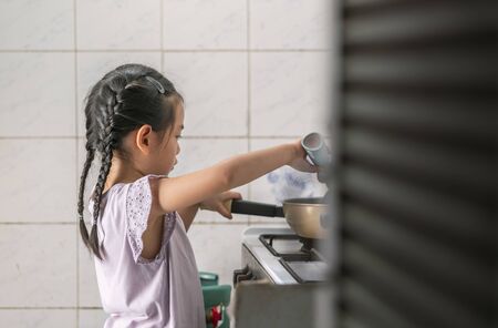 Asian little girl is cooking herself for the first time.の写真素材