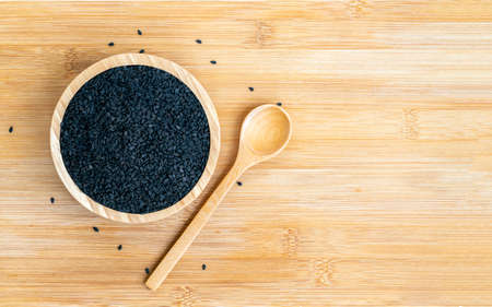 Top view black sesame seeds in wooden bowl with spoon on wooden table. Flat lay template design, space for copy.の写真素材