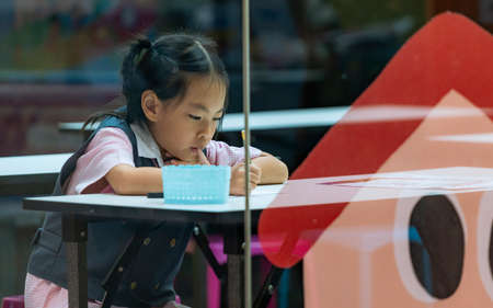 Asian kindergarten student focused on studying in after school class at private tutoring school in...