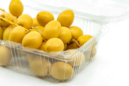 Close up fresh Date Palm fruit or Date fruit in cleared plastic box or container for sell on white...
