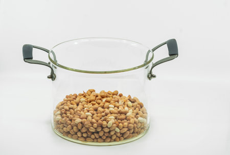 Raw organic peanuts in modern glass pot soup with metal handle on white background, clipping path around the modern glass pot soup.の写真素材