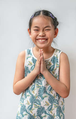 Portrait Asian child girl is greeting in Thailand traditional style that called Sawatdee. Asian...
