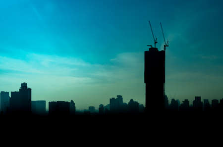 The landscape of silhouette of high rise building with the crane on top at sunrise in downtown of...