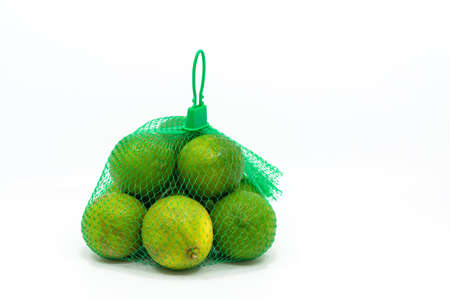 Seedless green lemons in a mesh bag, isolated organic green lemons on white background.の写真素材