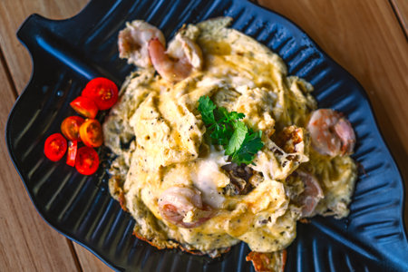 Thai food style of Scrambled eggs with shrimp over rice on a beautiful black leaf plate, decoration of small Coriander leave, top view image food on a wooden table.の写真素材