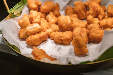 Deep-fried traditional Thai dough, deep-fried dough ready to serve for snack breakfast, warm light from above.の写真素材