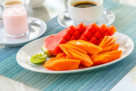 Beautiful sliced fruits in white plate on food table in the morning, artistic Thai style for fruit decoration, healthy Thai fruit, watermelon, papaya.の写真素材