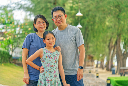 Portrait of Asian family with one child girl on the beach of Thailand, healthy middle-aged parent...