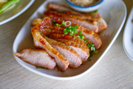 Grilled sliced pig neck in white plate with natural light, popular grilled meat of Thailand menu.の写真素材
