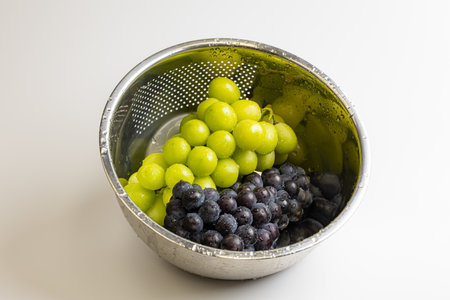 Close-up studio photo of juicy autumn grapes in a silver container.
