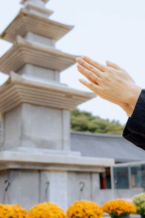 A woman's hand praying in front of the stone pagoda at Jangansa Temple in Gijang, Busan, South Korea.の写真素材