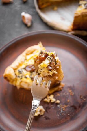 Caramelized garlic tart with goat cheese and herbs on dark wooden backgroundの写真素材
