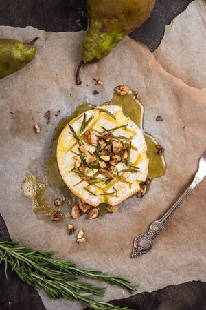 Delicious beautiful baked camembert with honey, walnuts, herbs and pearsの写真素材