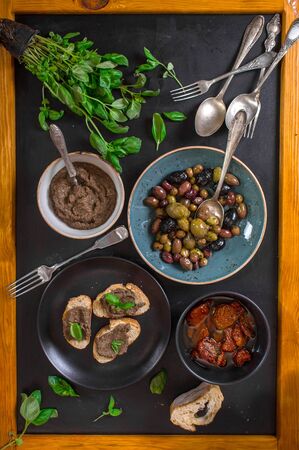 Table served with bread, tapenade, assorted olives, dried tomatoes in olive oil and basil. Dinner table with french provence appetizers and canapesの写真素材