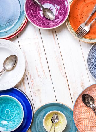 Vintage multicolored empty plates and bowls on a gray linen tablecloth. With antique spoons and forks. Space for text. Table setting. Shabby chic/retro style. Top view. Rustic kitchen. Copy spaceの写真素材