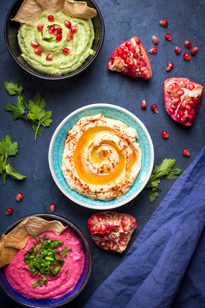 Colorful hummus bowls. Different kinds of dips. Traditional hummus, herbs hummus, beetroot hummus, spread. Assorted meze and dips with crispy pita. Meze and snacks concept. Middle eastern snacks setの写真素材