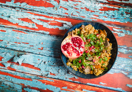 Rice pilaf with meat, chickpeas, vegetables, herbs, pomegranate. Space or text. Traditional Middle Eastern dish rice pilaf in bowl,  rustic wooden background. Top view. Closeup. Middle Eastern/Indianの写真素材