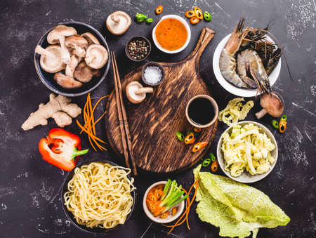 Asian food cooking concept. Empty wooden board, noodles, vegetables stir fry, shrimps, sauces, chopsticks. Asian/Chinese food. Top view. Ingredients for making Asian/Chinese dinner. Chinese noodlesの写真素材