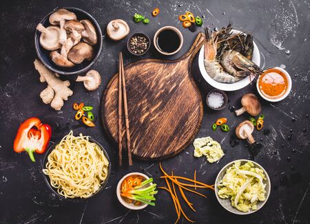 Asian food cooking concept. Empty wooden board, noodles, vegetables stir fry, shrimps, sauces, chopsticks. Asian/Chinese food. Top view. Ingredients for making Asian/Chinese dinner. Chinese noodlesの写真素材