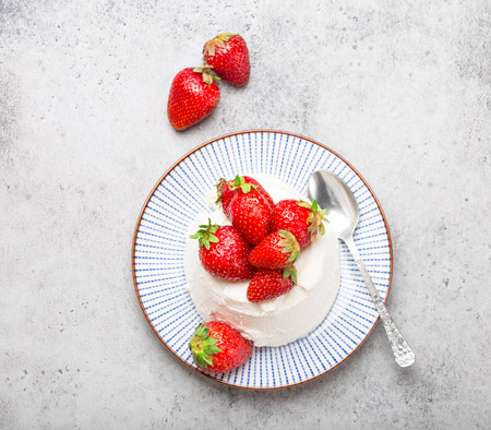 Top-view of fresh Italian cheese ricotta with strawberries on a plate with a spoon, grey rustic stone background, light summer dessert or snack, good for diet or healthy eating. Close-upの写真素材