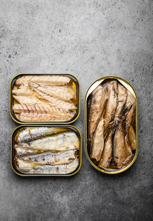 Assorted canned fish in a tin over gray concrete background: sardine, smoked sardine, mackerel. Tinned fish as a convenient, fast, healthy food and source of omega-3 fatty acids, protein and vitamin Dの写真素材