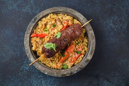 Traditional Middle Eastern meat Kebab with rice in rustic metal plate on blue rustic background top view. Arab meal for lunch or dinner, Middle Eastern cuisine .の写真素材