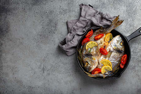 Grilled fish sea bream or dorado in cast iron skillet copy spaceの写真素材