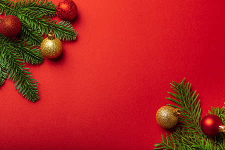 Christmas decorations and fir tree branch on red background