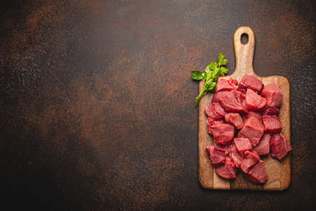 Beef raw meat cubes for stew on wooden cutting board copy spaceの写真素材