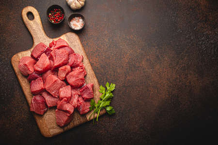 Beef raw meat cubes for stew on wooden cutting board copy spaceの写真素材