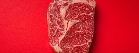 Raw meat beef prime cut steak Ribeye on clean red background from above, beefsteak concept banner minimalismの写真素材