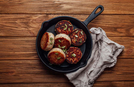 Homemade cutlets from fish, chicken or meat on black cast iron frying pan skillet