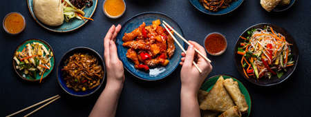 Set of Chinese dishes on table, female hands holding chopsticksの写真素材