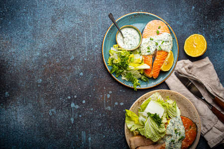 Healthy food meal grilled salmon steaks with dill sauce and salad leafs on two platesの写真素材