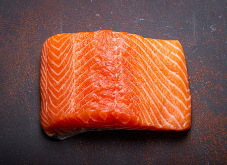 Piece of Norwegian raw salmon fillet on dark brown rustic background top view, healthy nutrition and...
