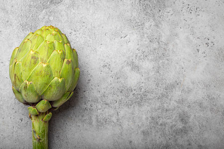 Fresh raw organic farm one artichoke on grey rustic stone background top view, healthy artichokes in balanced nutrition, cooking conceptの写真素材