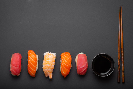 Traditional Japanese sushi top view with soy sauce and chopsticks on dark black minimal background. Sushi with salmon, tuna, shrimp, space for textの写真素材