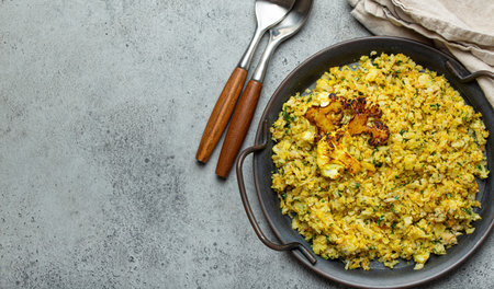 Fried cauliflower rice or couscous with dill on plate, healthy low carbohydrates vegetable side dish for keto diet and healthy low calories nutrition, rustic stone background, space for textの写真素材