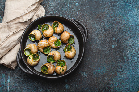 Escargots de Bourgogne Snails with Garlic Butter and Parsley in black cast iron pan on rustic stone background top view, traditional French Delicacy, space for text.の写真素材