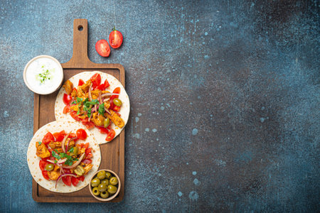Cooking Traditional Greek Dish Gyros: Pita bread with vegetables, meat, herbs, olives on rustic...