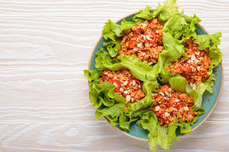Lettuce wraps filled with minced meat and topped with peanuts and chili pepper flakes on a plate, healthy protein dish, copy spaceの写真素材
