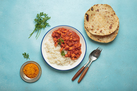 Indian chicken curry with basmati rice served on plate with chapati flatbread on the side top view