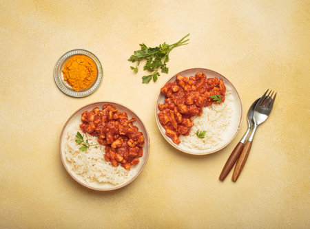 Indian chicken curry served with white rice and turmeric on yellow background top viewの写真素材