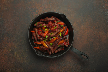 Lomo saltado, beef and red pepper stir fry cooking in cast iron pan, traditional Peruvian dishの写真素材