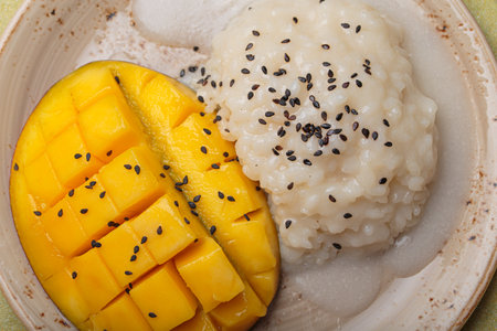 Traditional dessert of Thailand, delicious mango sticky rice with coconut milk and sesame seeds on tropical leaf top viewの写真素材
