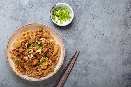 Dan dan noodles served with chopsticks and green onions top view, traditional Chinese Sichuan dish