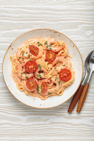 Seafood pasta linguine with shrimps and cherry tomatoes in creamy sauce garnished with parsley on white plate on white wooden background top viewの写真素材