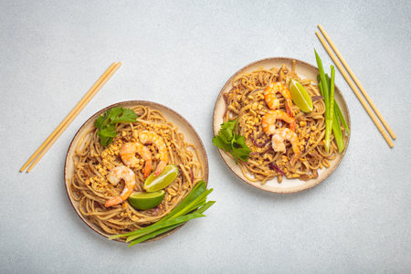 Traditional dish of Thailand, two bowls with Pad Thai noodles with shrimps and peanuts on a plate top view.の写真素材