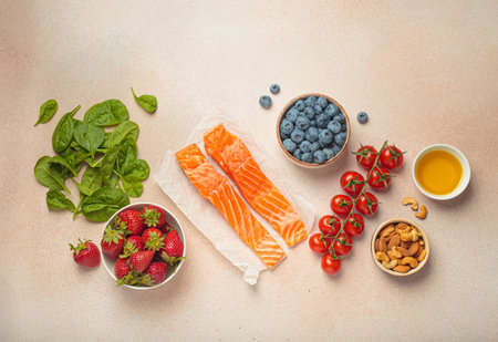 Healthy food for anti inflammatory diet: fish, vegetables, berries, nuts, olive oil, spinach top view on light beige backgroundの写真素材